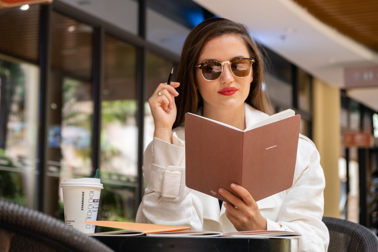 A woman with glasses reading one of Happy Hoos fall notebook