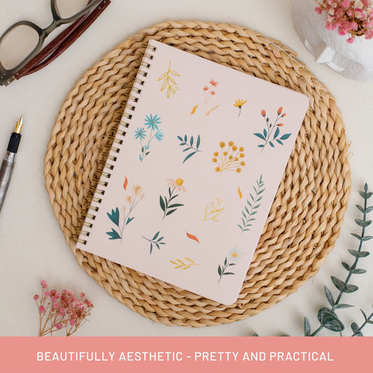 Summer Garden aesthetic spiral notebook styled flat lay on woven rattan placemat with pen and glasses—blush pink botanical floral cover, gold spiral binding, premium lined/college ruled notebook with 100 GSM thick paper, perforated pages, and laminated interior pockets for journaling, note taking, and planning. Perfect for teacher gifts, office/work notes, bullet journaling beginners, back-to-school stationery, and thoughtful summer birthday gifts.