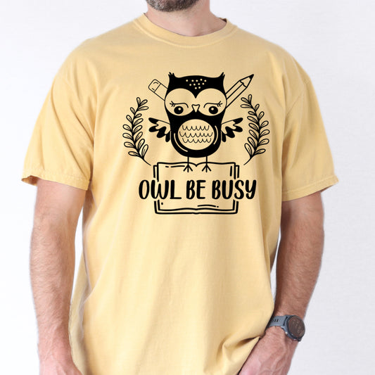 Person wearing butter colored t-shirt with an owl graphic and 'OWL BE BUSY' text.