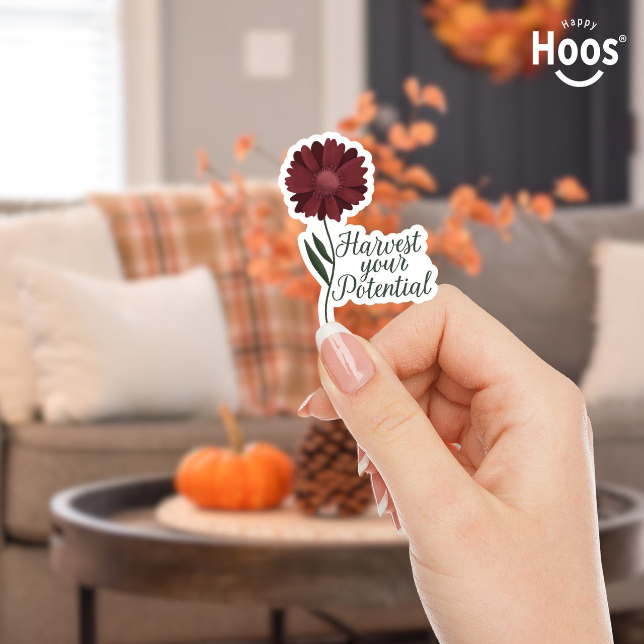 Hand holding Harvest Your Potential sticker featuring a deep burgundy gerbera daisy with detailed petals and green stem and leaves, with dark script lettering reading "Harvest your Potential" beside the flower, measuring 2.5 by 3.5 inches
