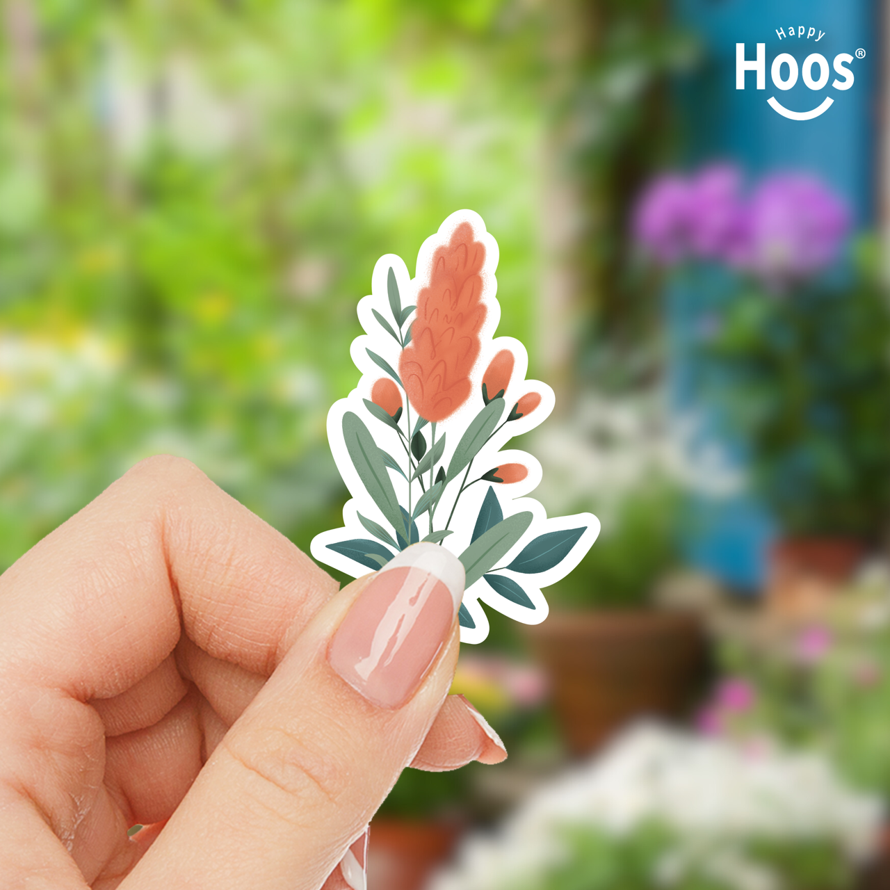 Hand holding a floral sticker with a blurred garden background