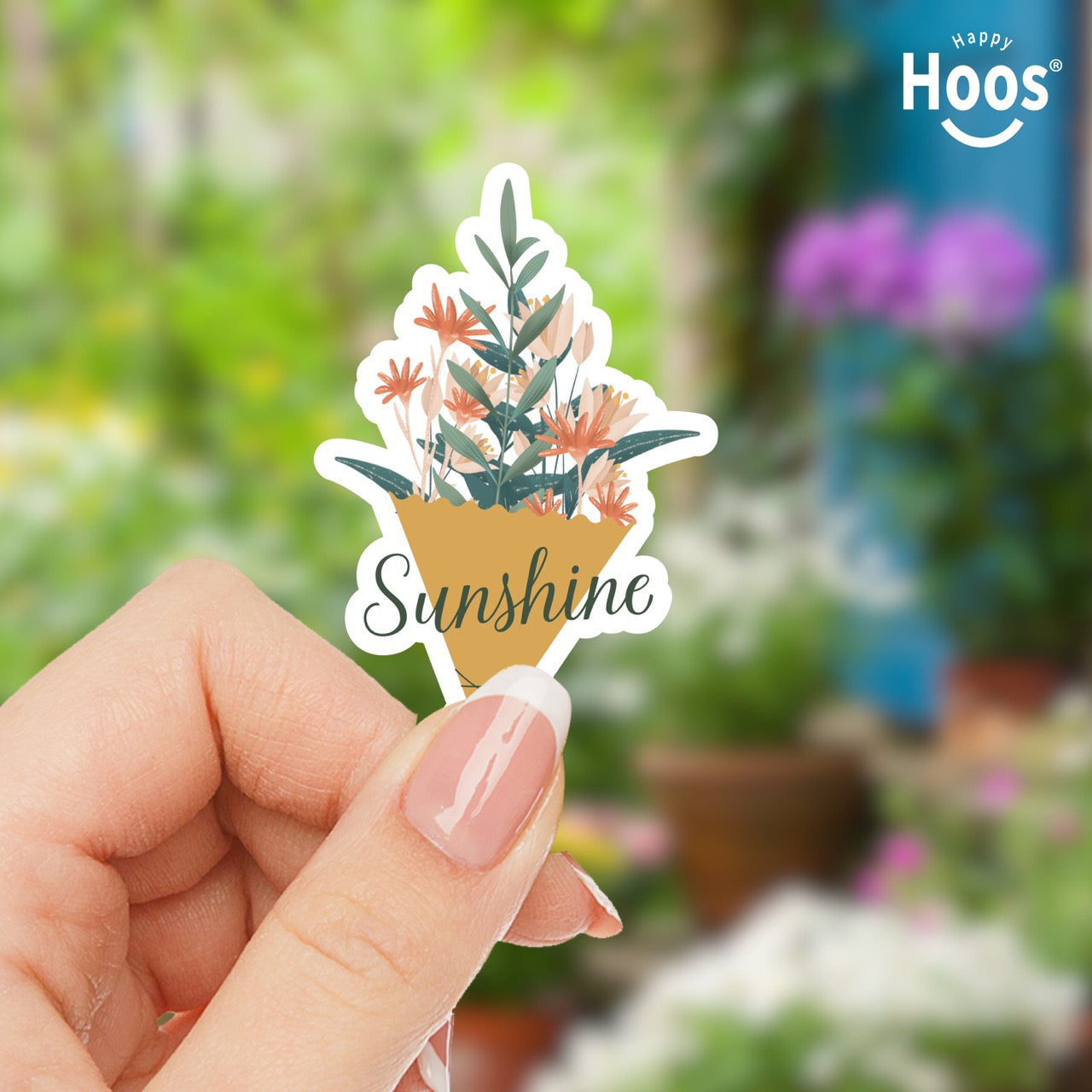 Hand holding a 'Sunshine' plant-themed sticker with a garden background