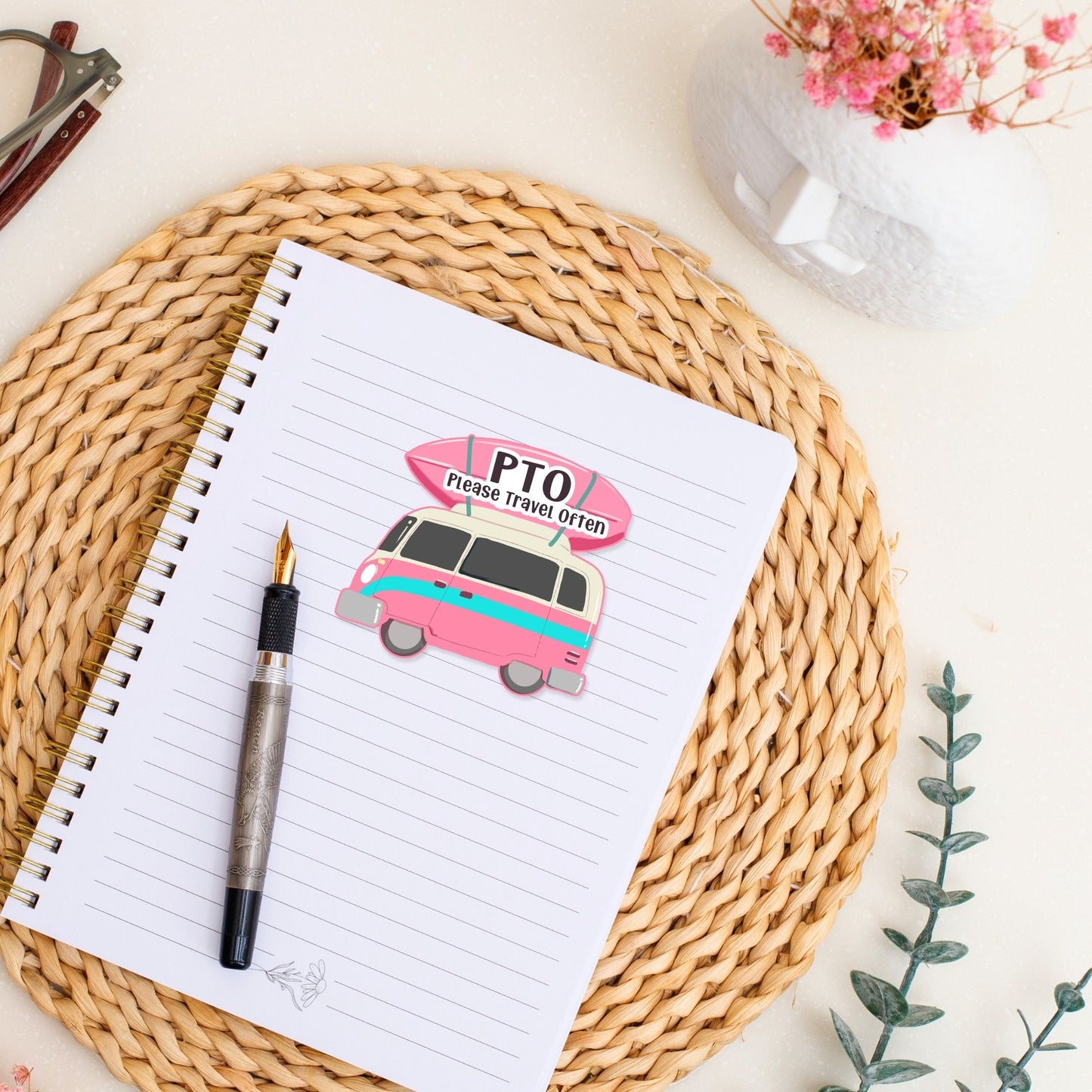 A  camper van sticker with the quote 'PTO please travel often' on top of a notebook.