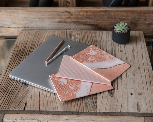 Laptop with a pink and white patterned cover on a wooden surface