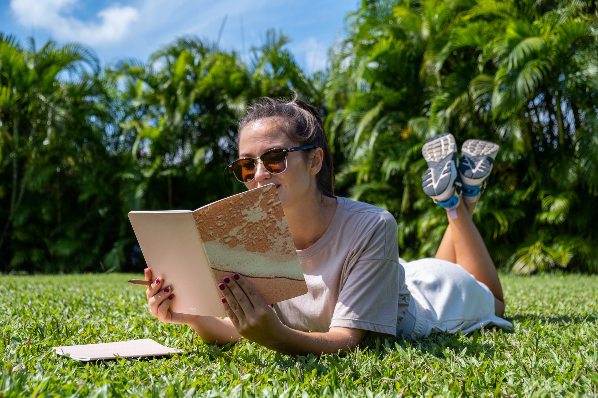 Woman reading a book outdoors on grass with trees in the background