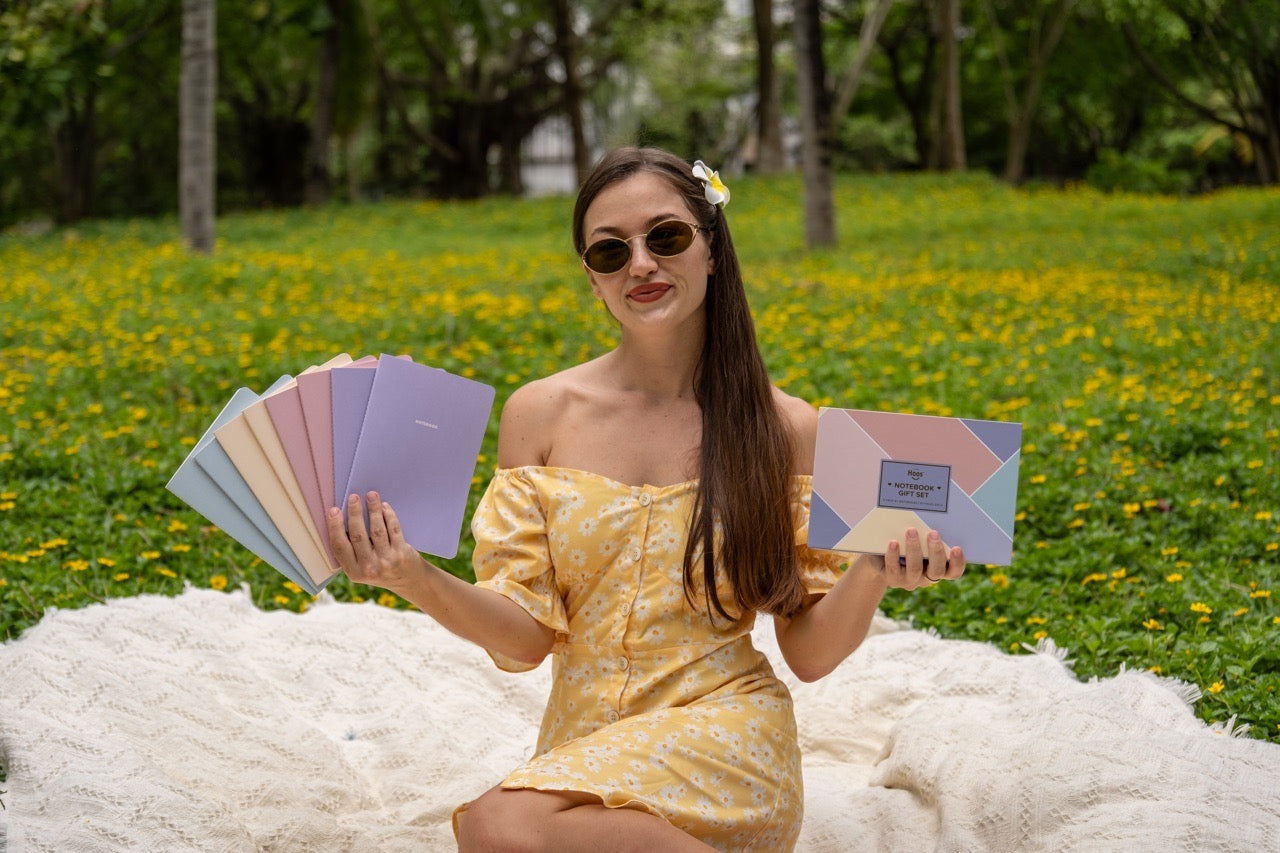 Woman holding Happy Hoos summer notebooks and box outdoors