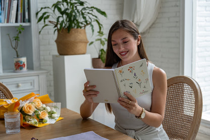 Woman reading a notebook at a table with a cozy indoor setting