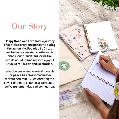 Notebooks with floral designs on a textured surface, with text about Happy Hoos brand and its mission.