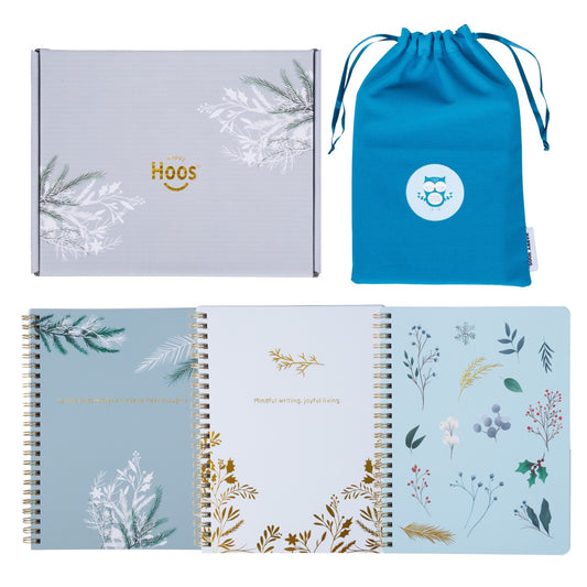 Three notebooks with winter themed floral designs, a box, and a blue drawstring bag on a white background