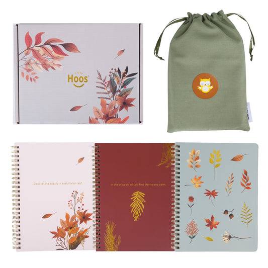 Set of notebooks with fall themed floral designs and a green drawstring bag and box 
on a white background