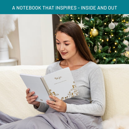 Woman reading a notebook on a couch with a decorated Christmas tree in the background