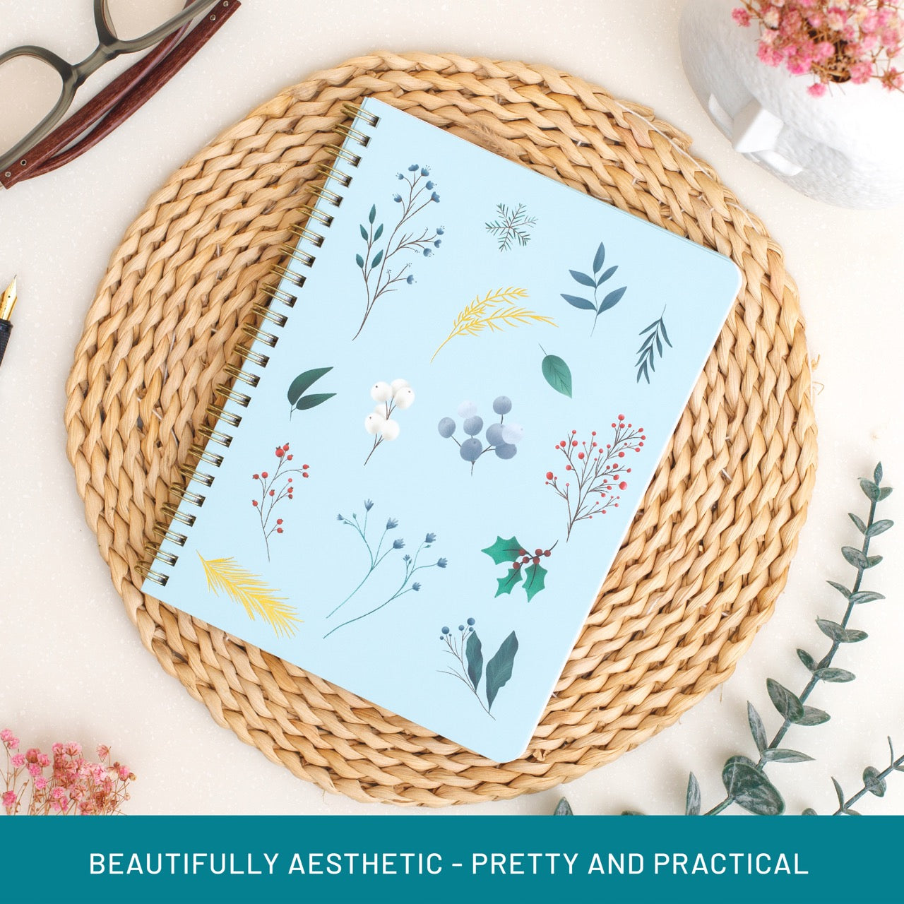 Notebook with floral design on a woven mat with decorative elements.