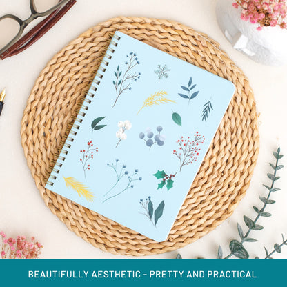 Notebook with floral design on a woven mat with decorative elements.