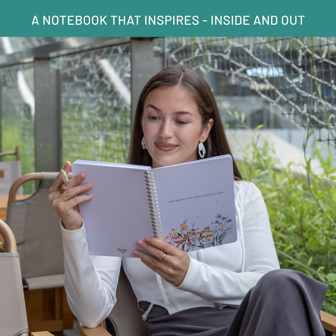 Woman reading a notebook with a scenic cover in an outdoor setting