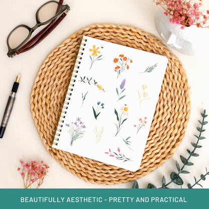 Notebook with floral design on a woven mat with glasses and pen, text 'BEAUTIFULLY AESTHETIC - PRETTY AND PRACTICAL'.