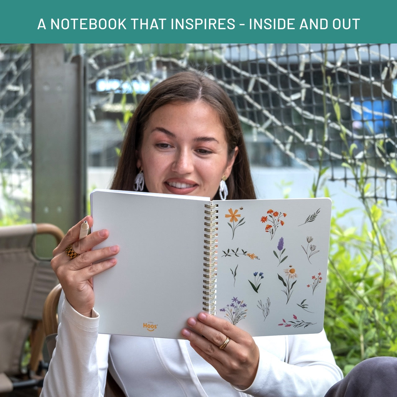 Woman holding a notebook with floral designs outdoors