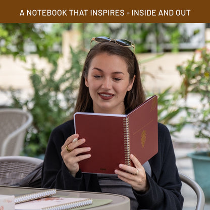 Woman holding a red notebook with a blurred outdoor background