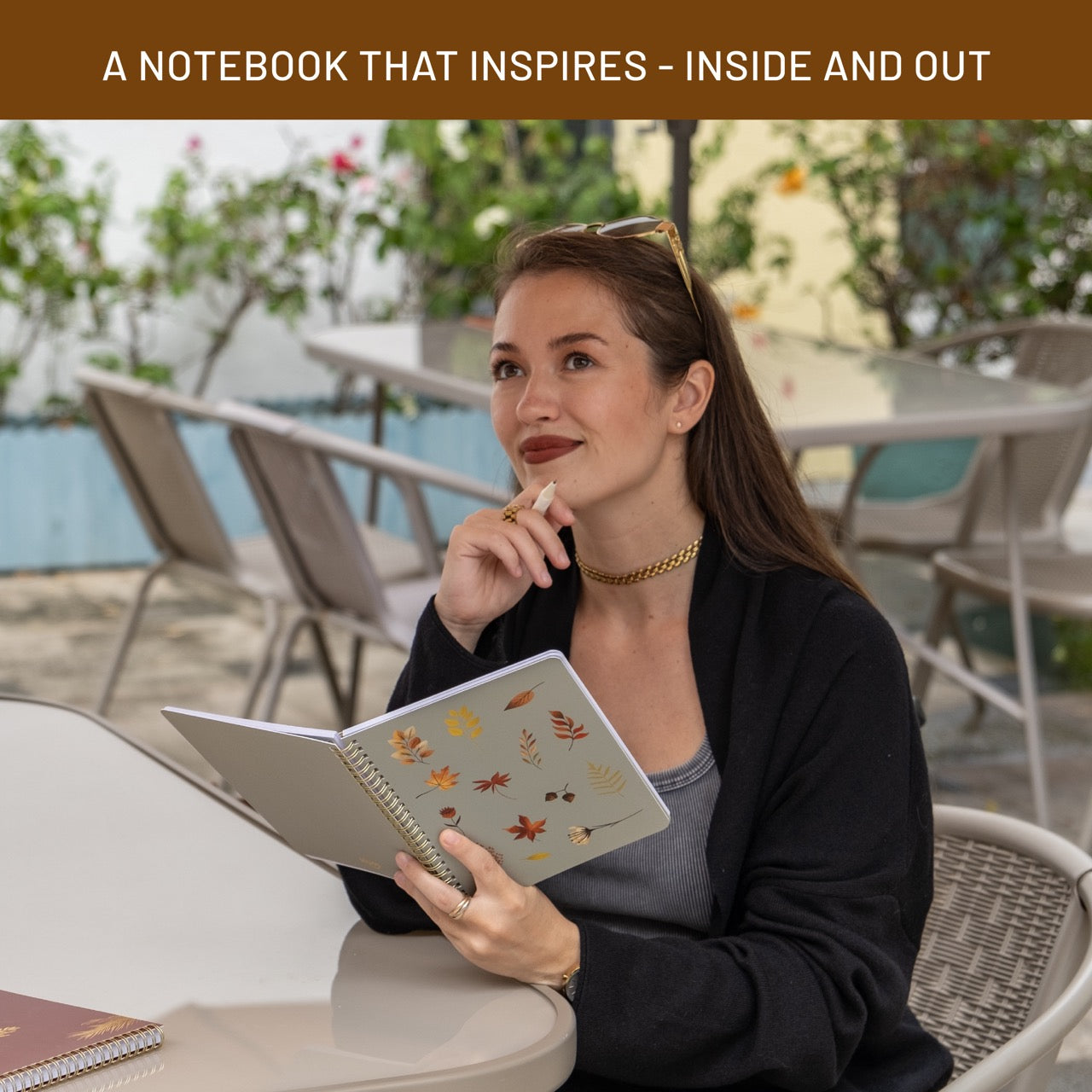 Woman holding a notebook with autumn-themed cover in an outdoor setting