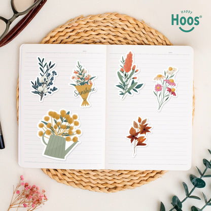 Botanical Florals stickers on open journal: winter botanical with berries, flower bouquet with "Sunshine", yellow flowers in watering can, coral botanical stem, colorful wildflower bouquet, orange autumn leaves