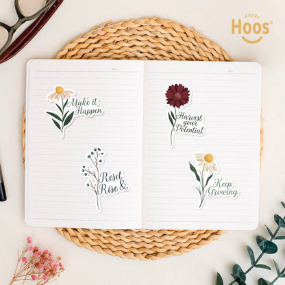 Four flower stickers in open journal: 'Make it Happen', 'Harvest your Potential', 'Reset Rise &', and 'Keep Growing' arranged on lined pages with woven placemat