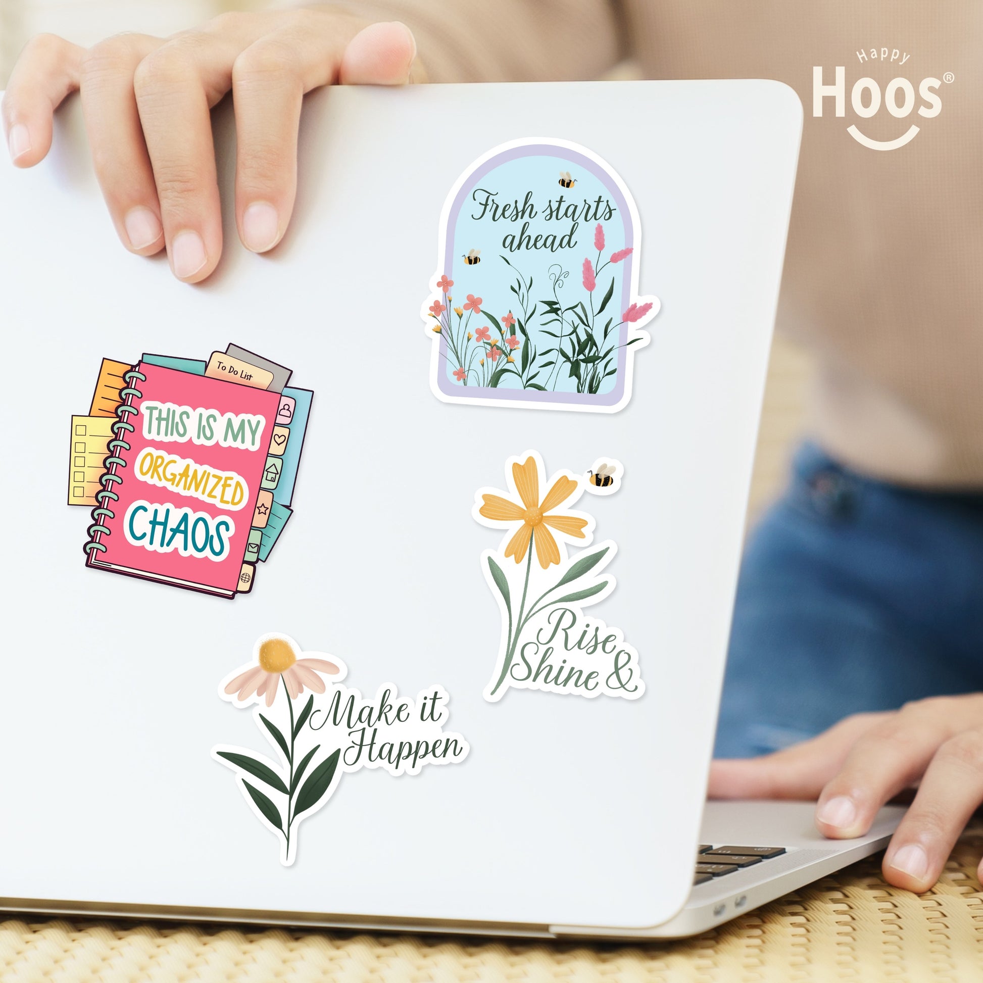 Four back to school stickers on white laptop: 'This is My Organized Chaos' planner, 'Fresh starts ahead' floral arch, 'Make it Happen' daisy, and 'Rise Shine &' yellow flower