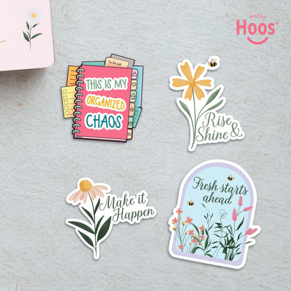 Four motivational stickers on textured surface: 'This is My Organized Chaos' planner, 'Rise Shine &' yellow flower, 'Make it Happen' daisy, and 'Fresh starts ahead' floral arch