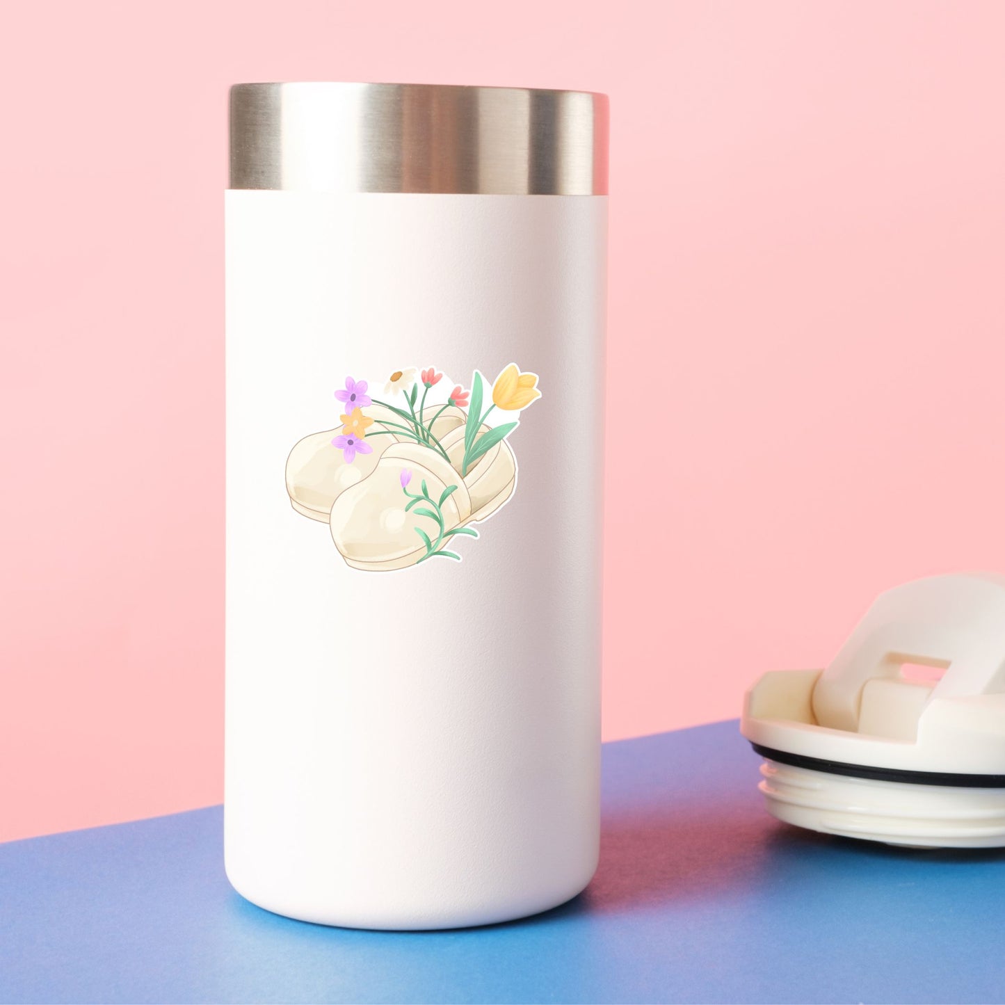 White tumbler with floral design on a pink and blue background