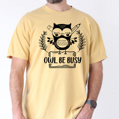 Person wearing butter colored  t-shirt with an owl graphic and 'OWL BE BUSY' text.