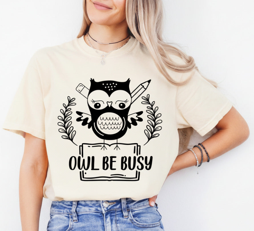Person wearing a beige t-shirt with an owl graphic and 'OWL BE BUSY' text.