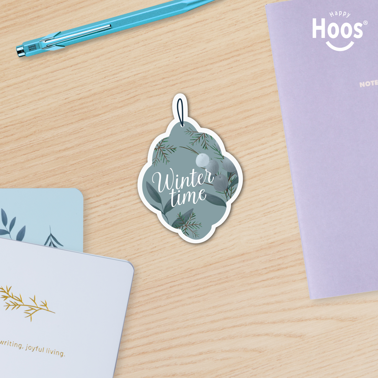 Winter Ornament Sticker with 'Winter time' text on a wooden surface with stationery items.