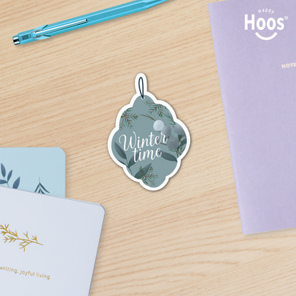 Winter Ornament Sticker with 'Winter time' text on a wooden surface with stationery items.