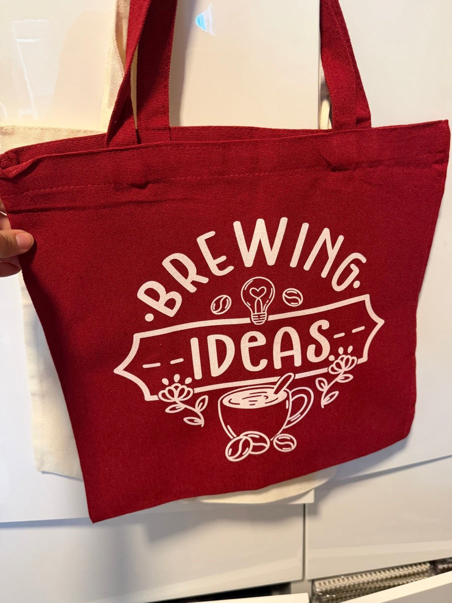 Red tote bag with 'Brewing Ideas' text and graphics on a white background