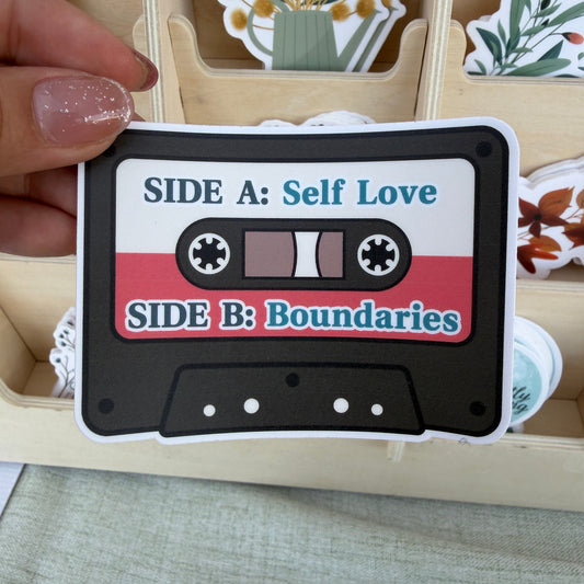 Cassette tape-shaped card with 'Self Love' and 'Boundaries' text, held by a hand.