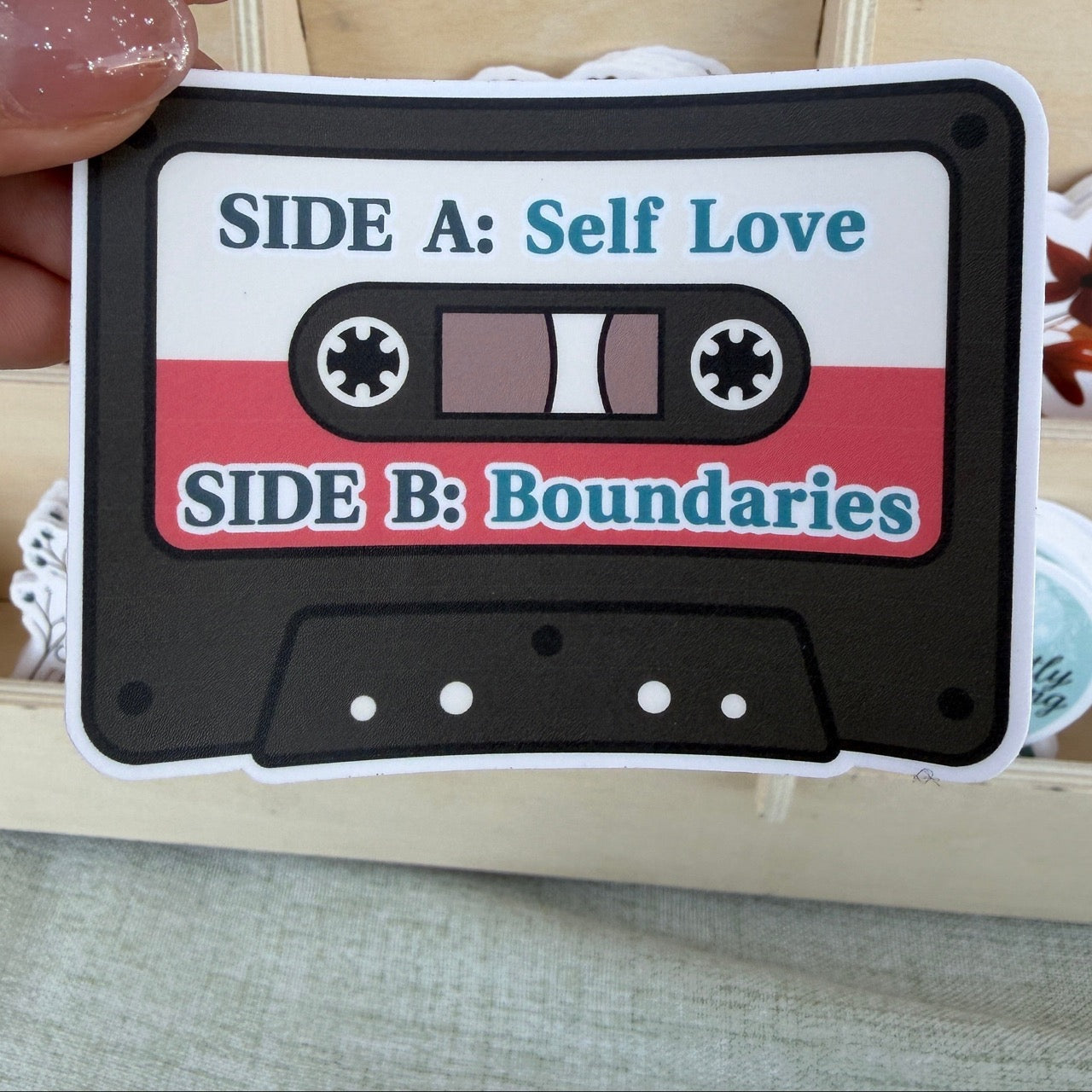 Cassette tape design sticker with 'Side A: Self Love' and 'Side B: Boundaries' text held by a hand.