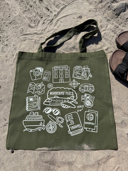 Green tote bag with travel-themed illustrations on a sandy surface - tote bag with theme on journaling and traveling