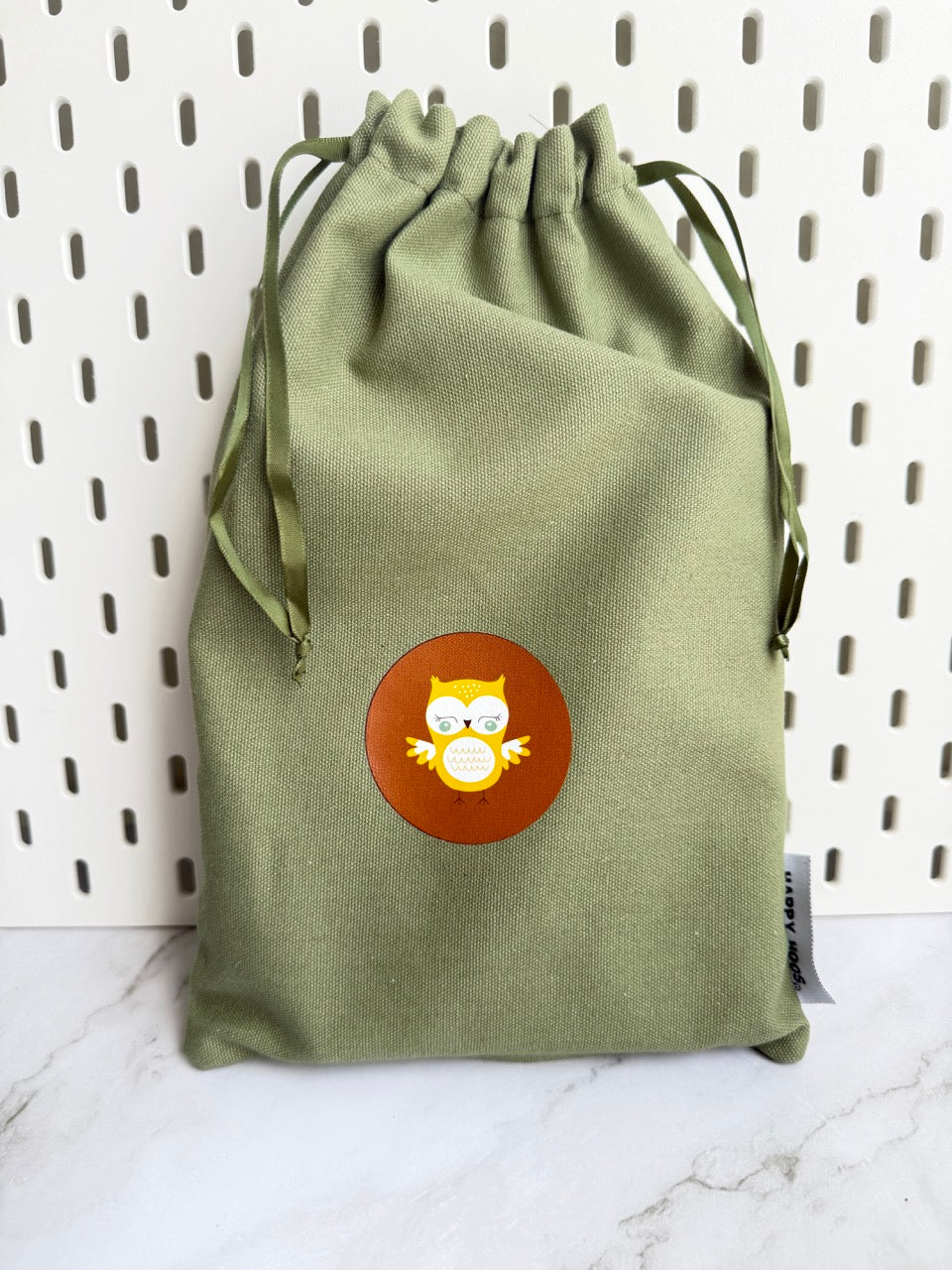 Fall themed - Green drawstring bag with a circular sticker featuring an owl design on a white background.