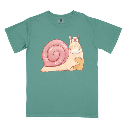 Light green t-shirt with an illustration of  snail holding a clipboard and wearing a nurse's hat and face mask.