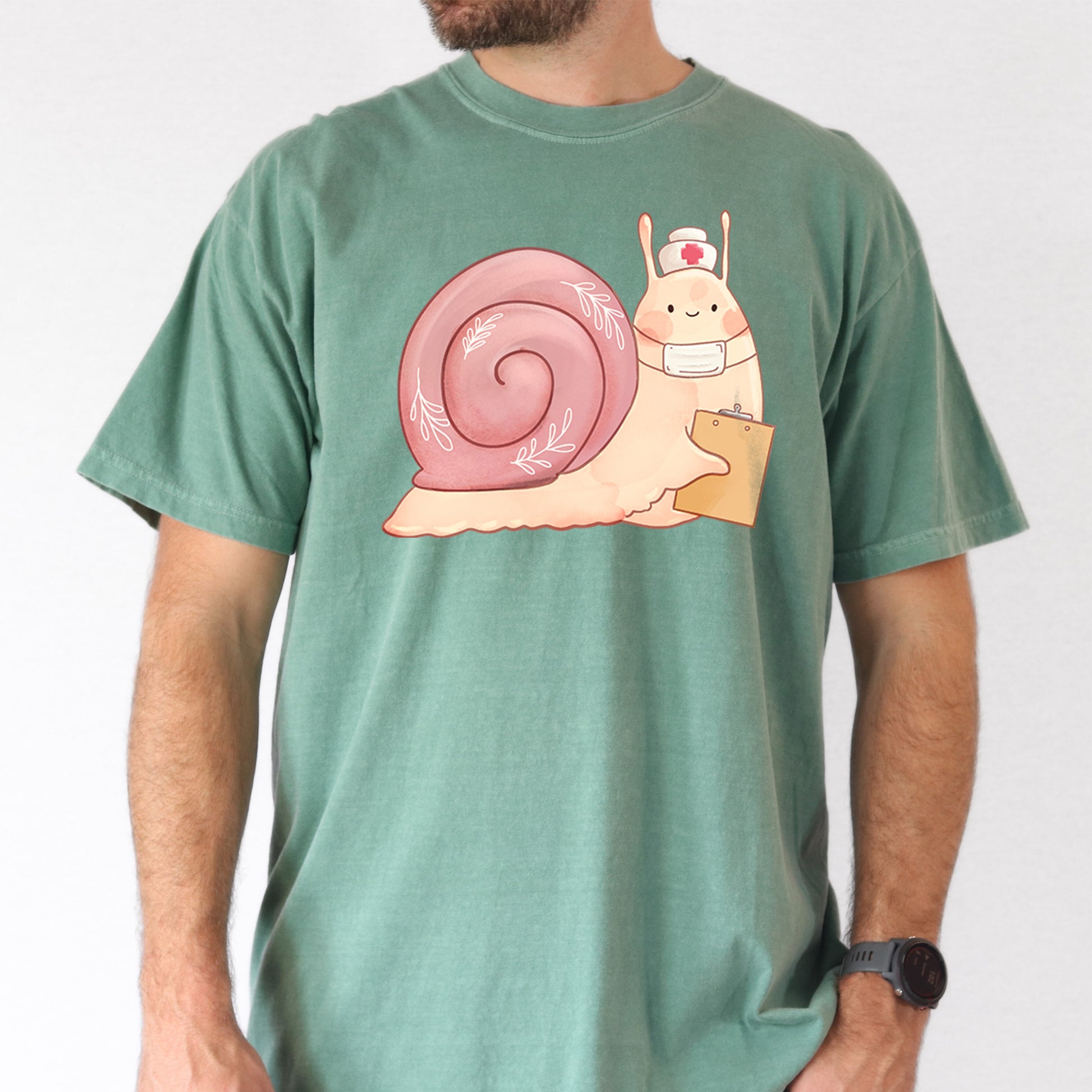 Man wearing light green t-shirt with an illustration of  snail holding a clipboard and wearing a nurse's hat and face mask.