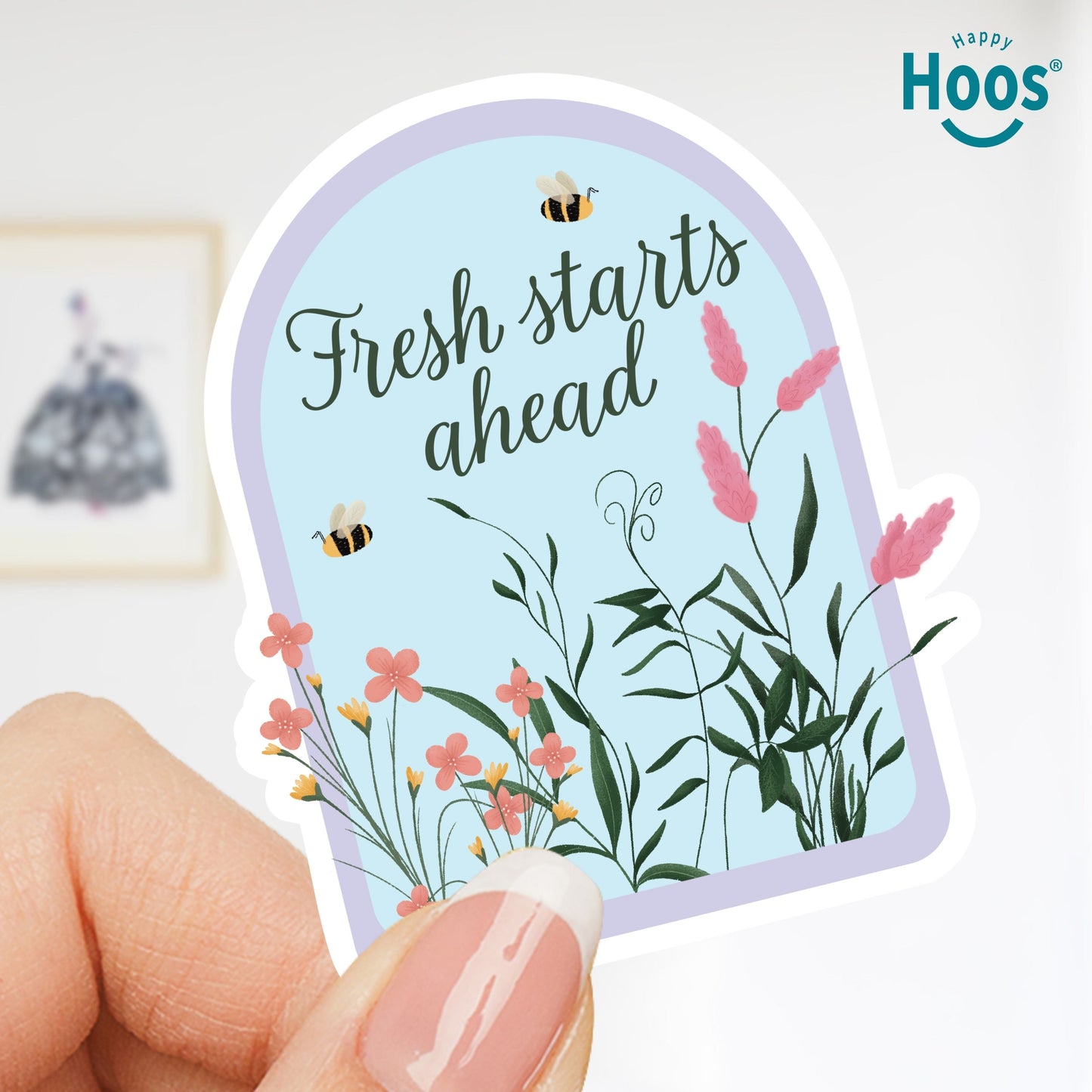 Hand holding a decorative sticker with floral design and 'Fresh starts ahead' text, with 'Happy Hoos' branding.