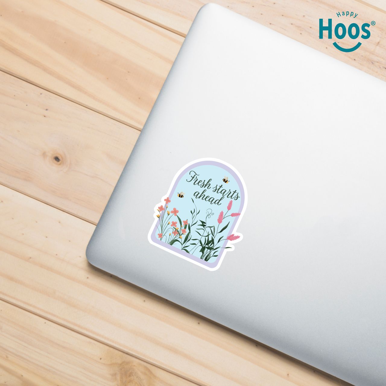 Laptop with a 'Fresh starts ahead' sticker on a wooden surface, featuring the 'Happy Hoos' brand.