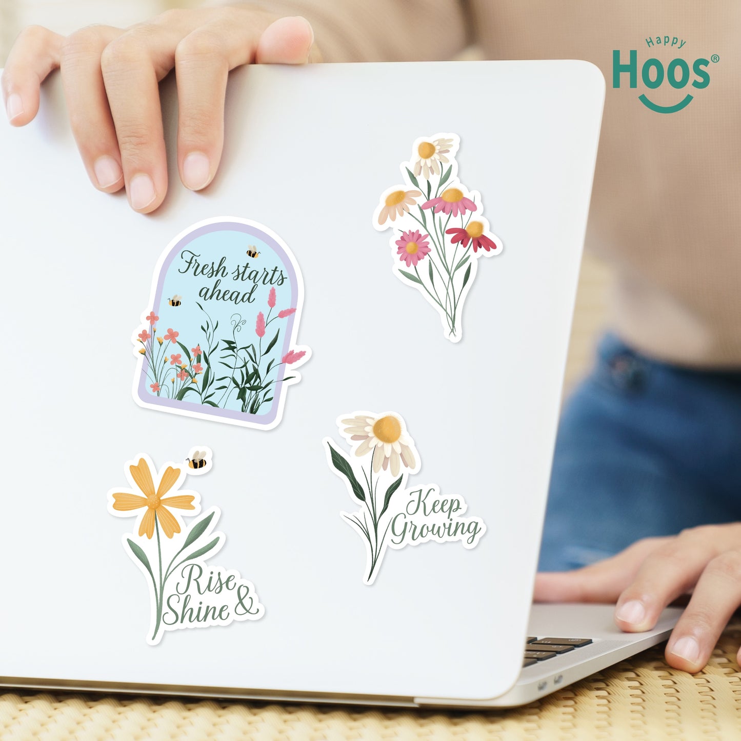 Laptop decorated with spring stickers: garden dome with "Fresh starts ahead", colorful wildflower bouquet, daisy with bee and "Rise & Shine", daisy with "Keep Growing"