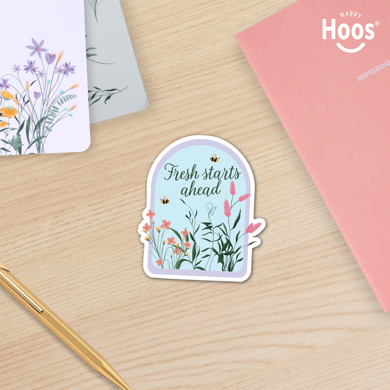 Sticker with 'Fresh starts ahead' text on a wooden surface with stationery items.