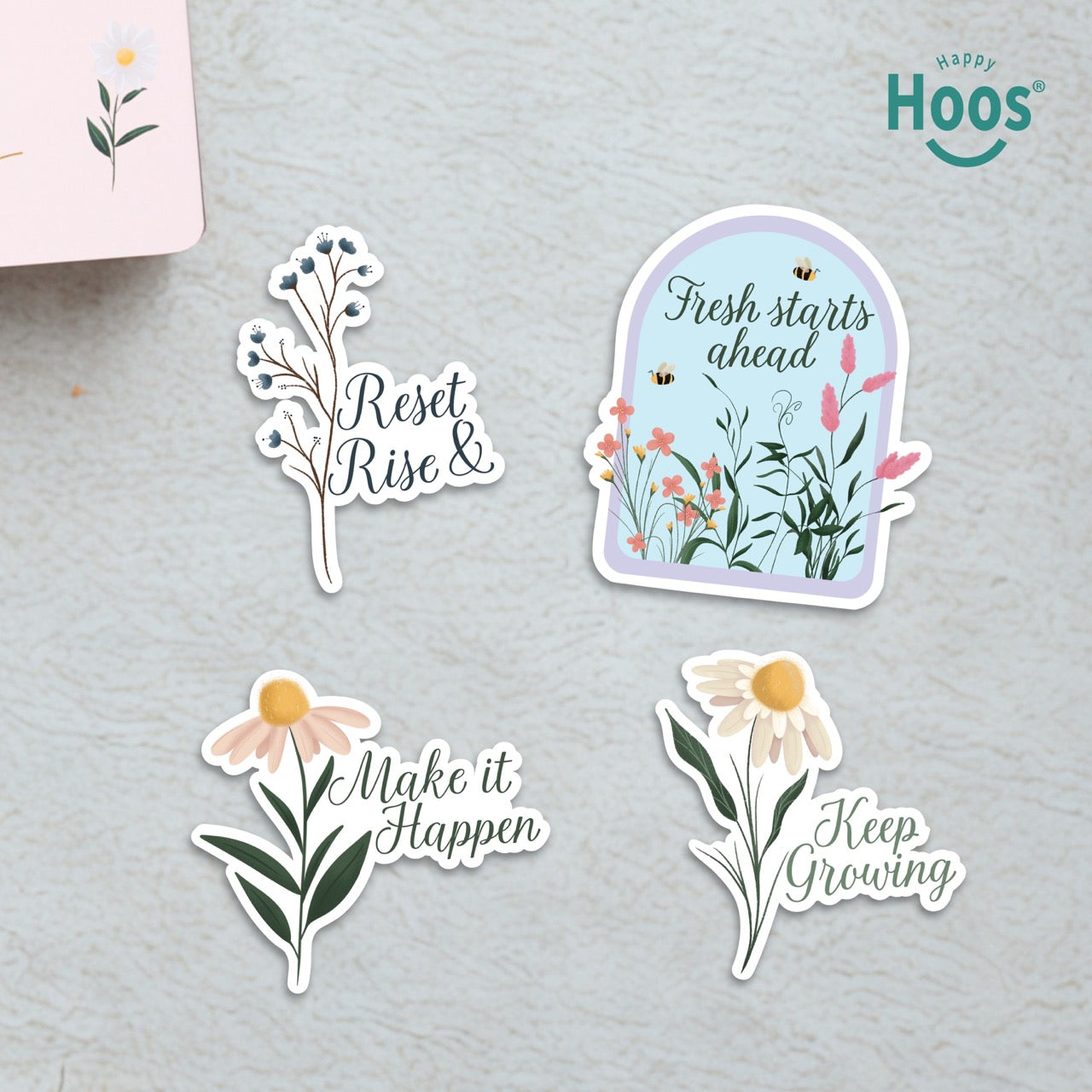 Set of motivational stickers with floral designs and text on a gray surface, featuring the brand 'Hoos'.  The following text are presented in each sticker: Reset & Rise, Fresh Starts Ahead, make it Happen, Keep growing. 