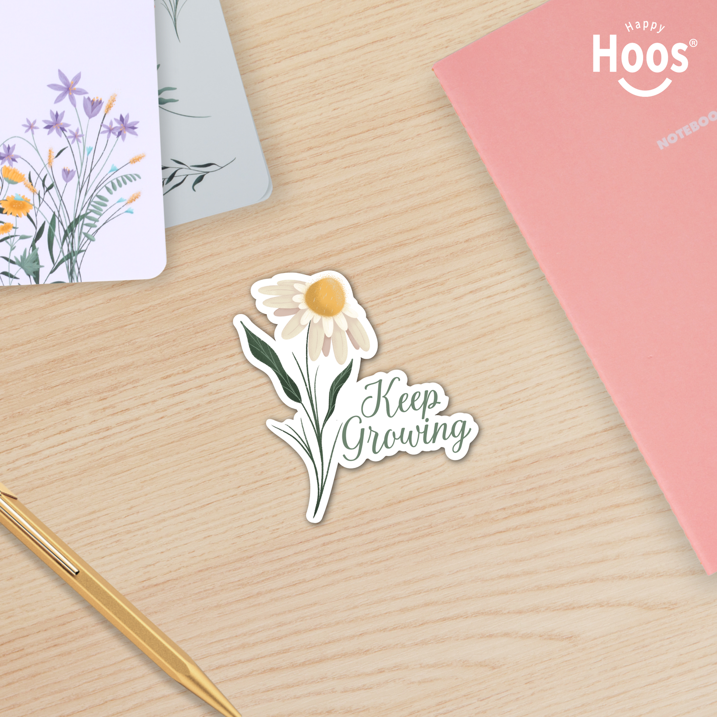 Decorative sticker with floral design and text on a wooden surface with stationery items.  "Keep Growing" spring sticker 