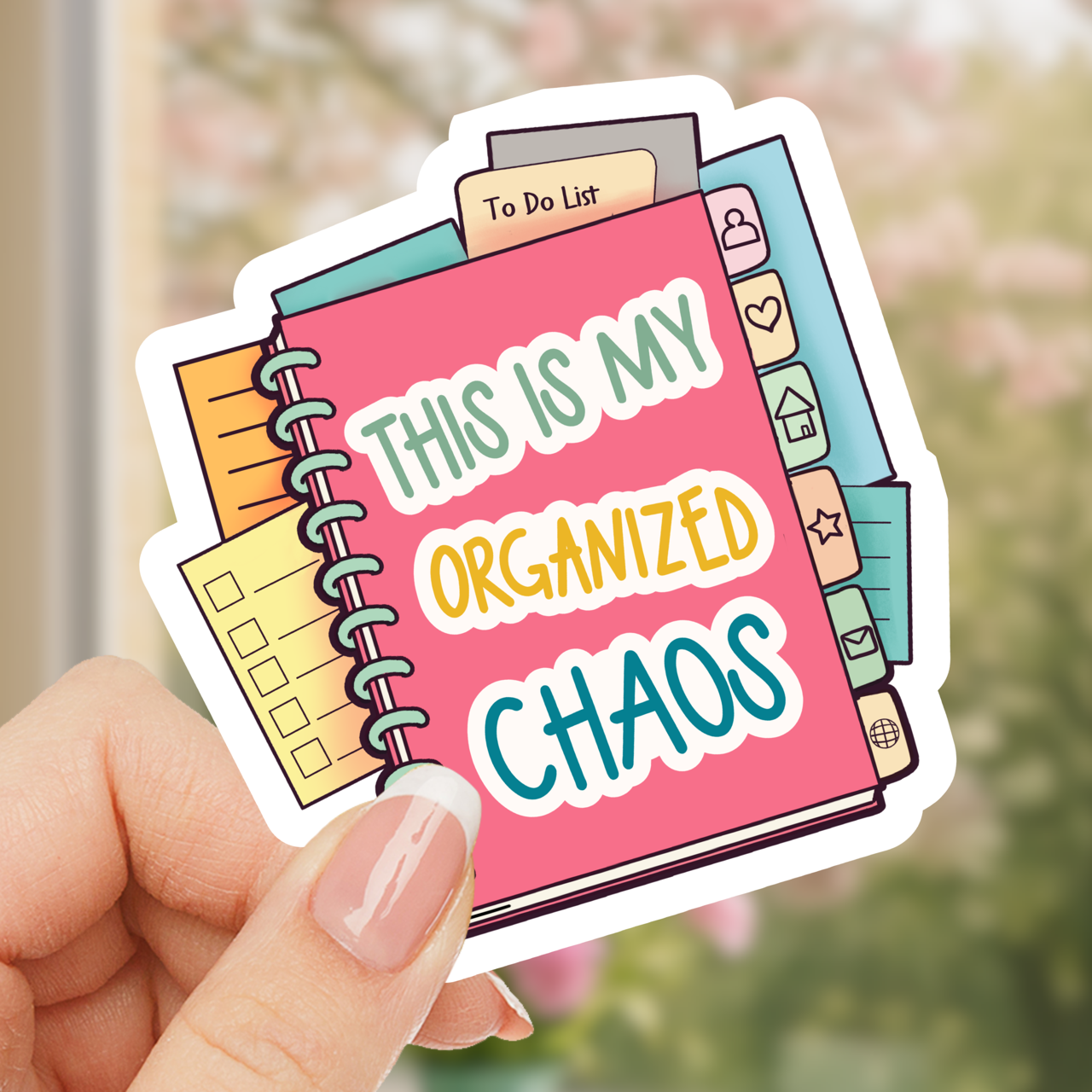 Sticker of a notebook with 'This is my organized chaos' text held by a hand.