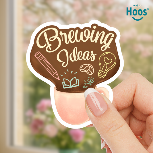 Hand holding a sticker with 'Brewing Ideas' text and illustrations, with 'Happy Hoos' brand visible.