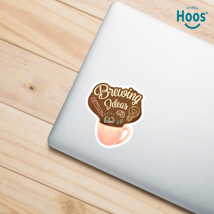 Laptop with a 'Brewing Ideas' sticker on a wooden surface, featuring the 'Happy Hoos' brand.