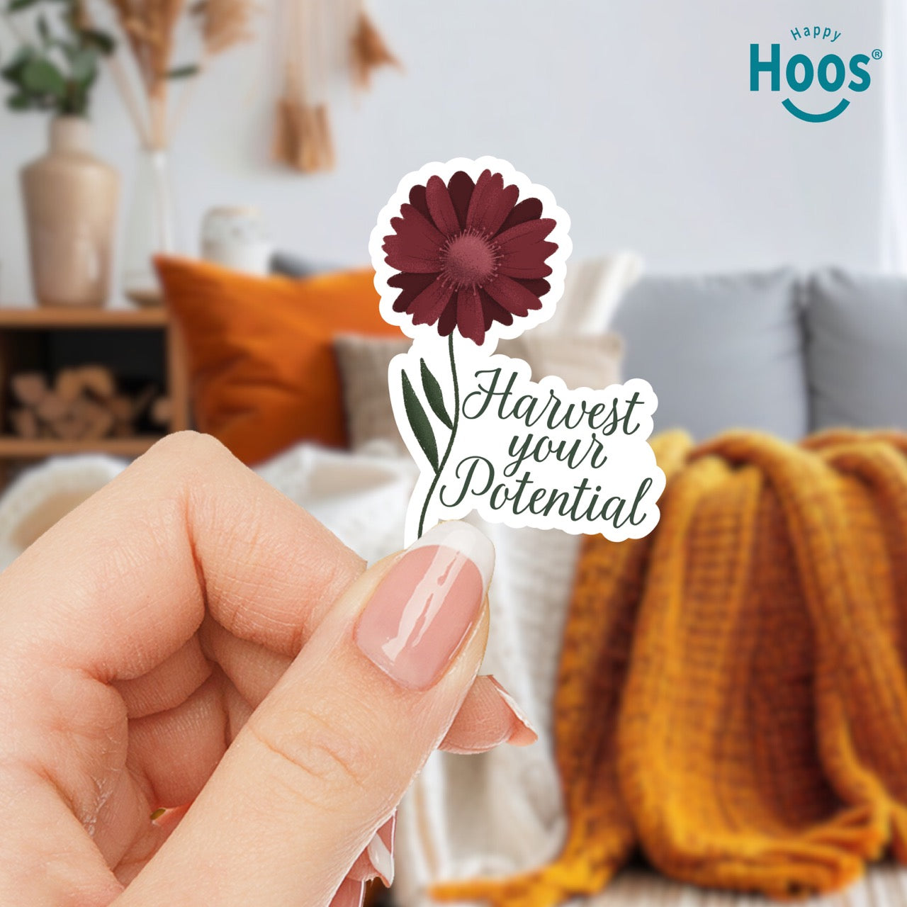 Hand holding Harvest Your Potential sticker featuring a deep burgundy gerbera daisy with detailed petals and green stem and leaves, with dark script lettering reading "Harvest your Potential" beside the flower, measuring 2.5 by 3.5 inches
