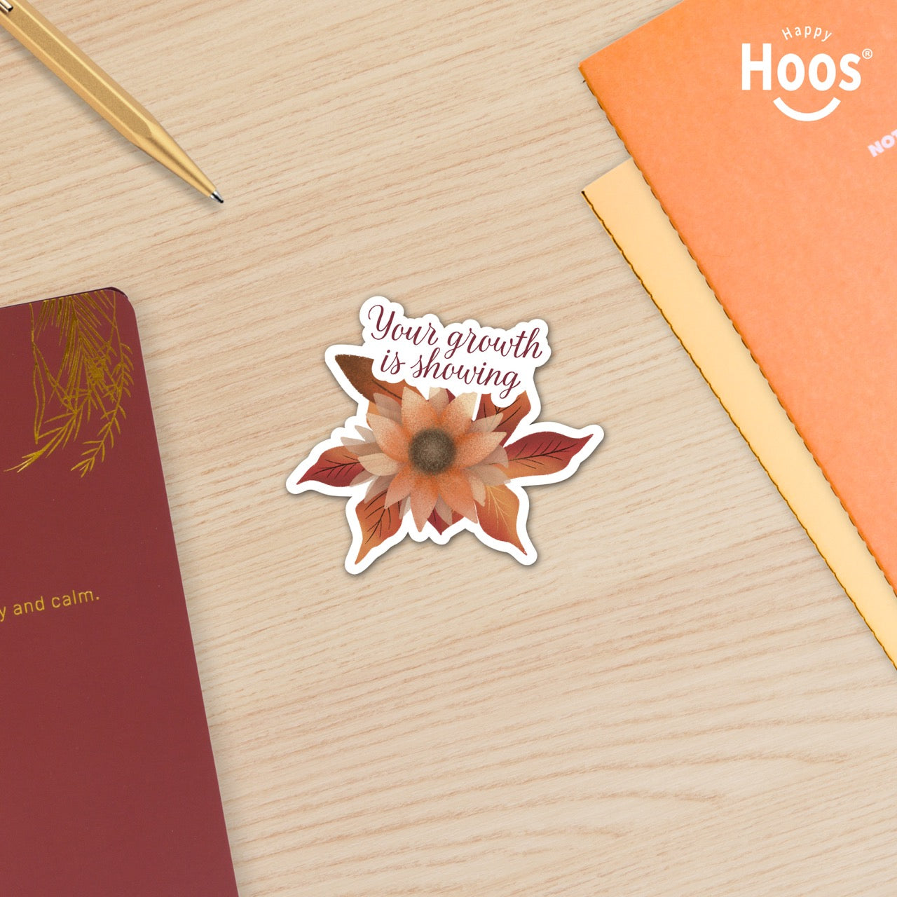 Autumn Growth sticker featuring a watercolor sunflower in autumn tones of orange, rust, and brown with fall leaves, and burgundy script lettering reading "Your growth is showing" at the top, measuring 3.3 by 2.9 inches surrounded by Happy Hoos fall notebooks