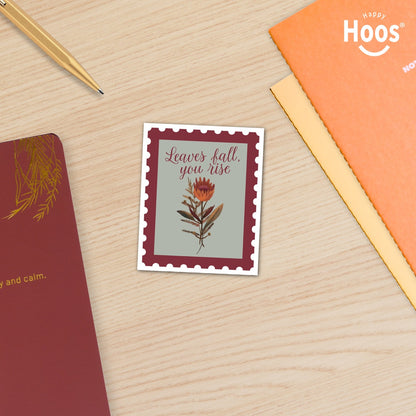 Decorative sticker with floral design and text on a wooden surface with stationery items.